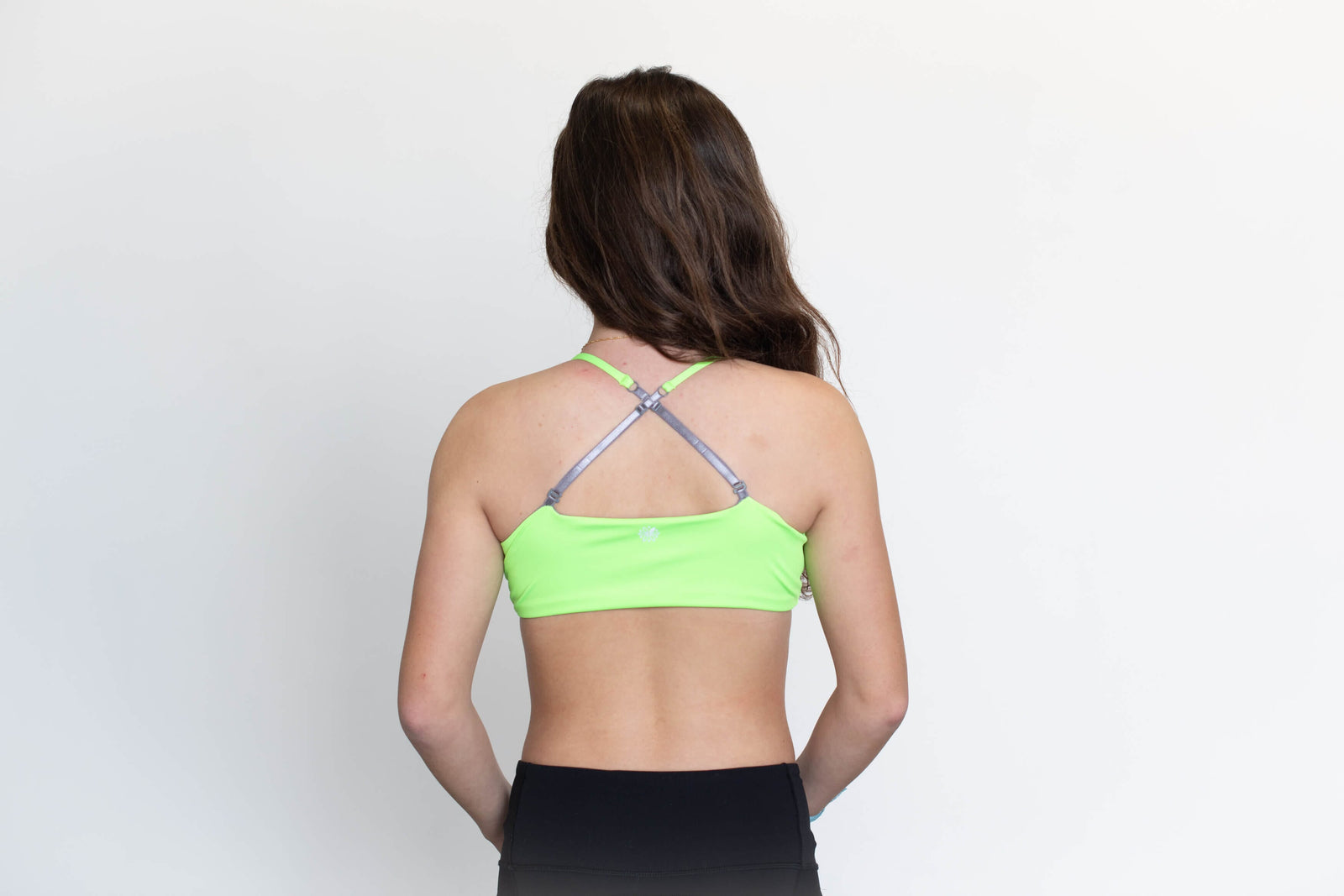 Image of a teenage girl with her back to the camera, wearing a Lime-Silver Bleum Active Bra, a sports bra available at Bleuet.