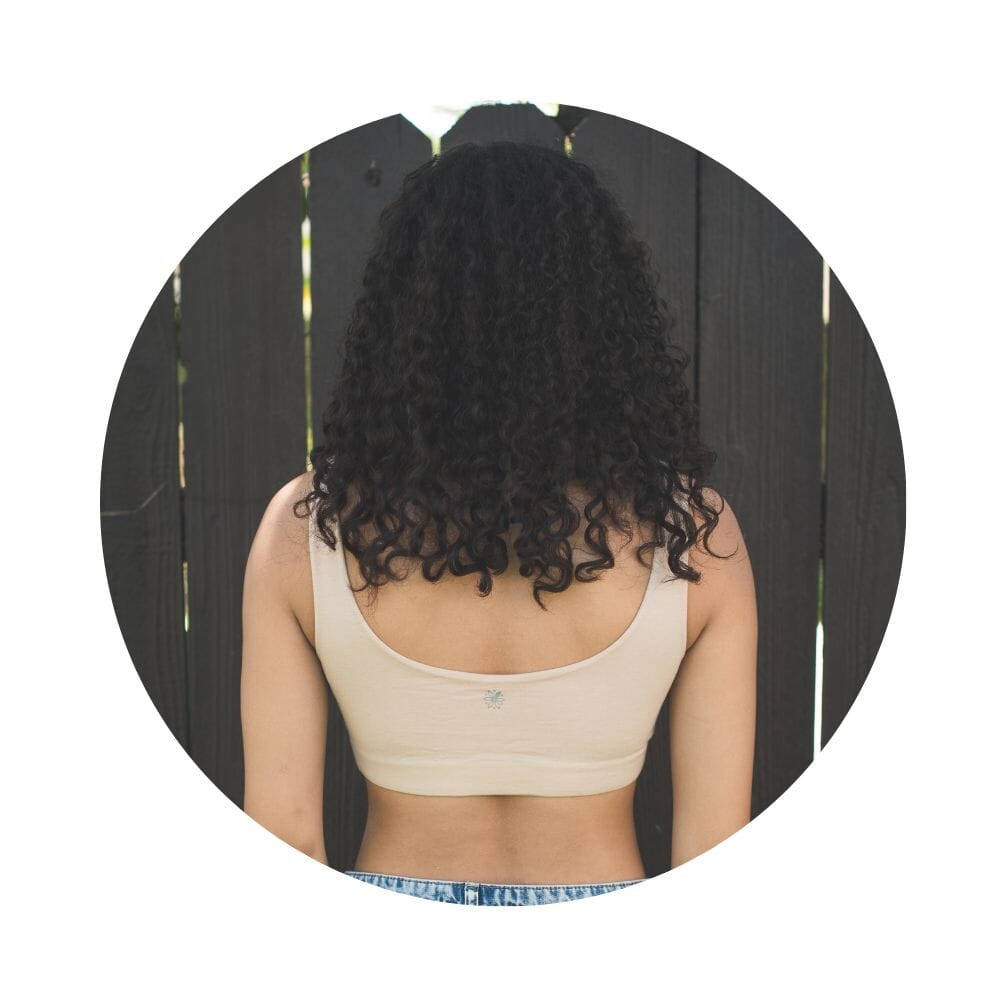 Sand-Rose# A young woman with blonde hair smiling and looking over her shoulder, wearing an Sand-Rosecolor aster organic tank bra.