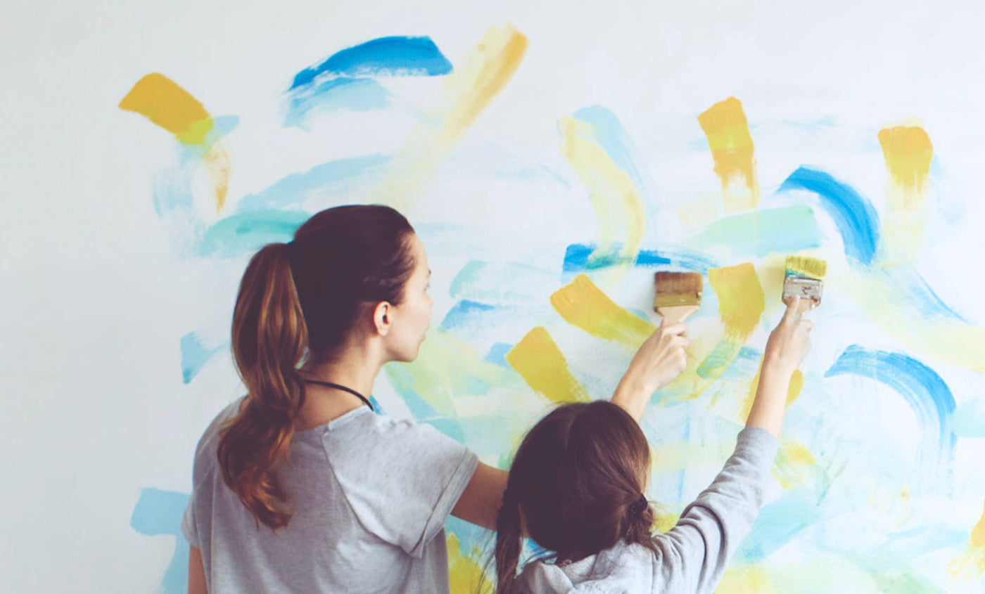Mother and daughter painting a wall together and investing time together