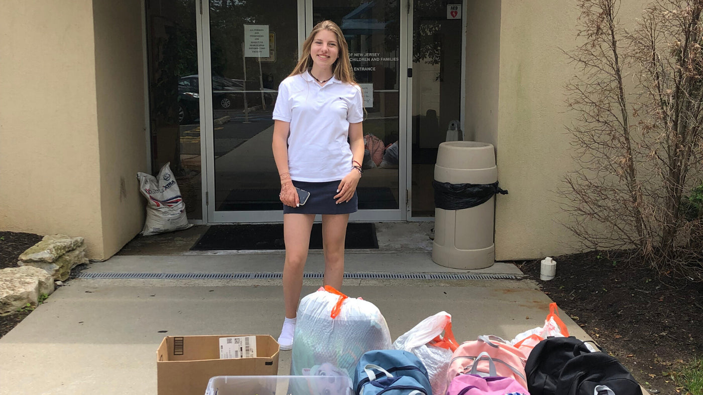 Girl standing with Backpacks for Hailey's Haven. Hailey O'donnell is a Bleuet Girl and founder of the non-profit Hailey's Haven.