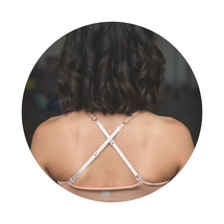 Close-up back view of a person with shoulder-length hair wearing a beige Bleum Active Bra with crisscross straps.