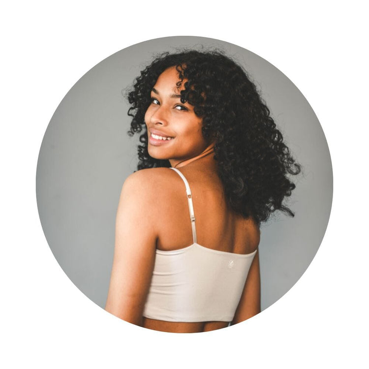 A girl with curly hair wearing a dove cami bra, viewed from the back.