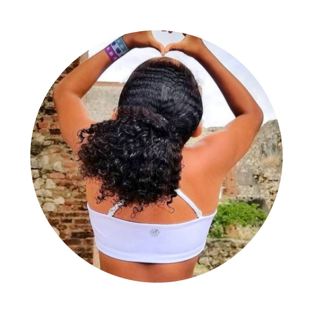 White-Pink#Young girl with curly hair forming a heart shape with her hands, wearing a white Bleum Active Bra, in an outdoor setting.