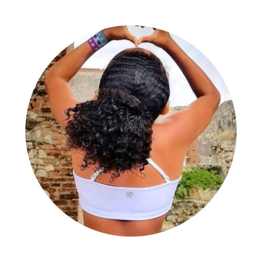 White-Pink#Young girl with curly hair forming a heart shape with her hands, wearing a white Bleum Active Bra, in an outdoor setting.