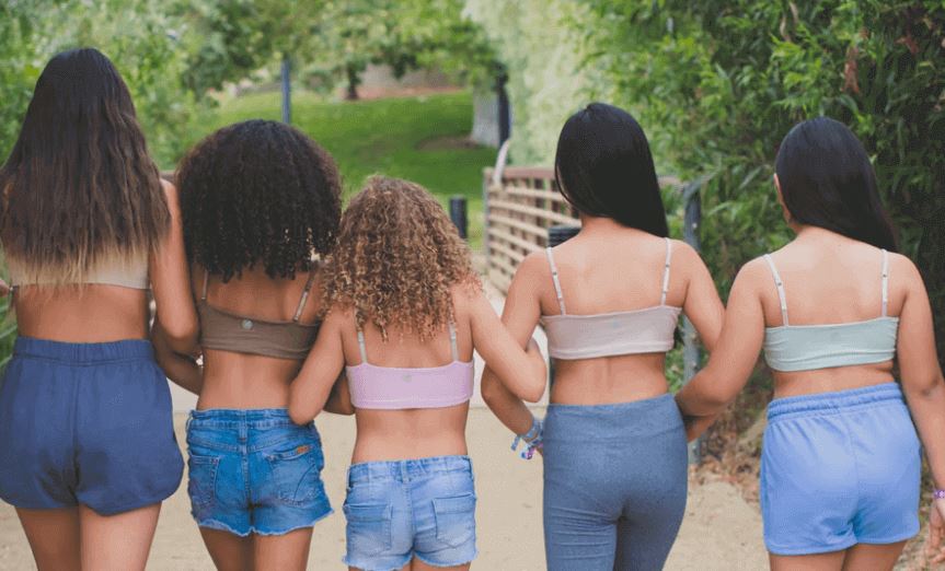 A group of teen girls walking arm in arm away from the camera into a park, wearing a variety of Bleuet Bleum Bamboo bras. Image from <a href="https://bleuetgirl.com/pages/bleuet-apparel" target="_blank">Bleuet</a>.