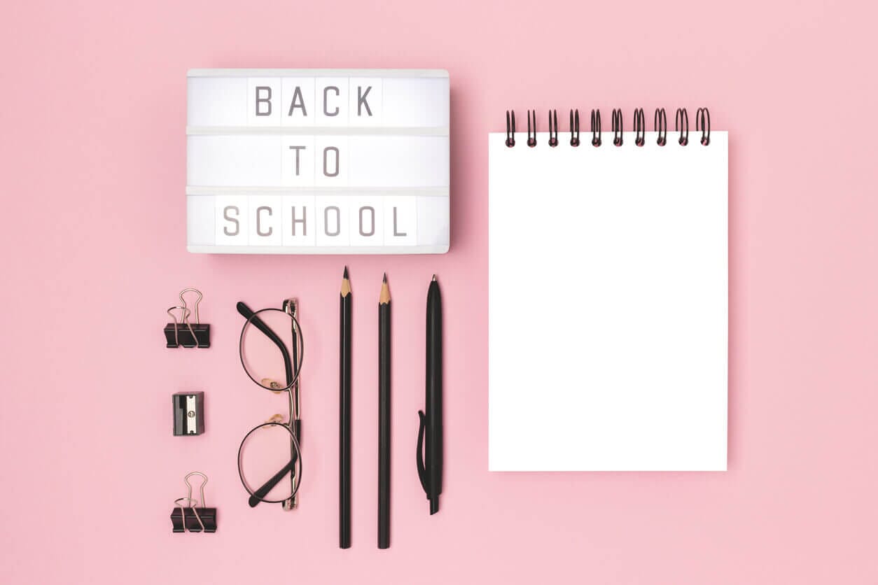 Image of a sign saying “BACK TO SCHOOL,” along with school accessories in front of a pink background, such as pencils, a pen, and a notebook, illustrating some of the items included in a back-to-school checklist.