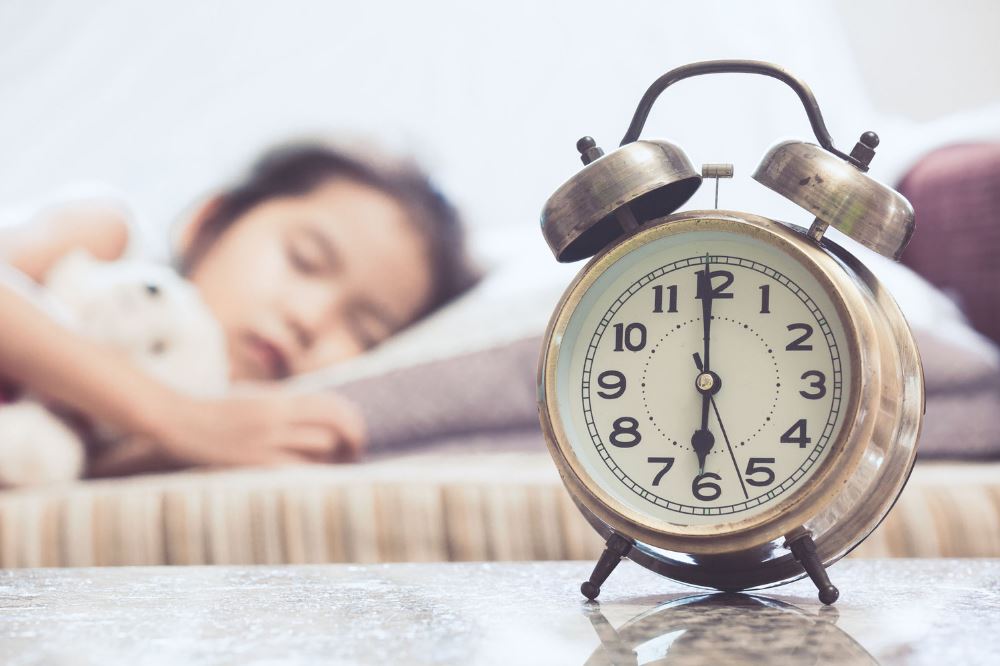 Tween girl sleeping soundly with an alarm set to ring