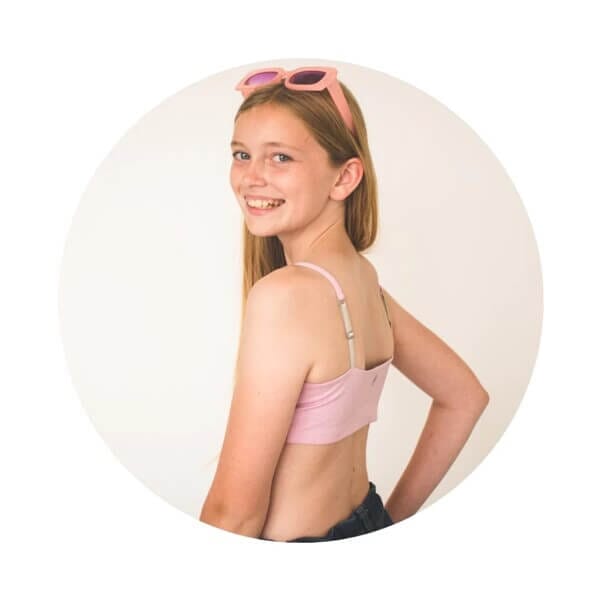 Young girl wearing a reversible Bleum Girls Bralette in pink toffee from the Bleuet website.