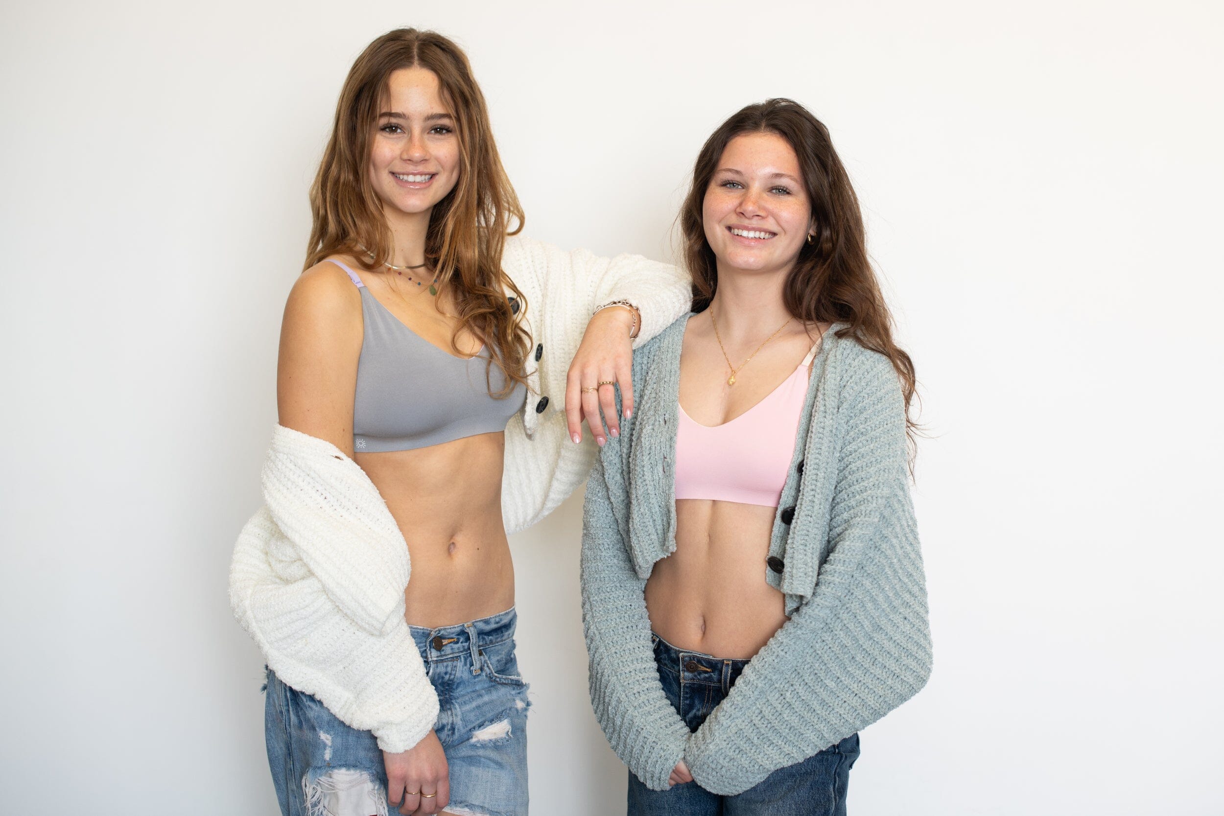 Two young women standing side by side, smiling at the camera. 