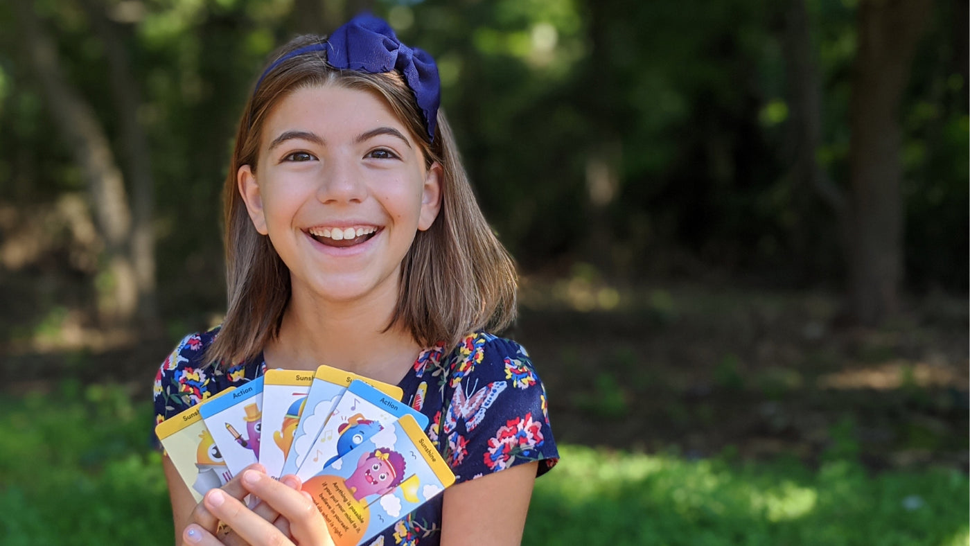 Eva Thompson is holding her Sun for Good cards designed to to help kids deal with stress and anxiety .