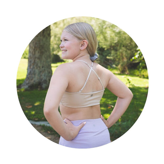 Sand-Sherbert#Close-up back view of a person with shoulder-length hair wearing a beige Bleum Active Bra with crisscross straps.