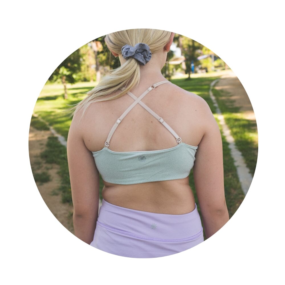 Sand-Sherbert#Close-up back view of a person with shoulder-length hair wearing a green Bleum Active Bra with crisscross straps.