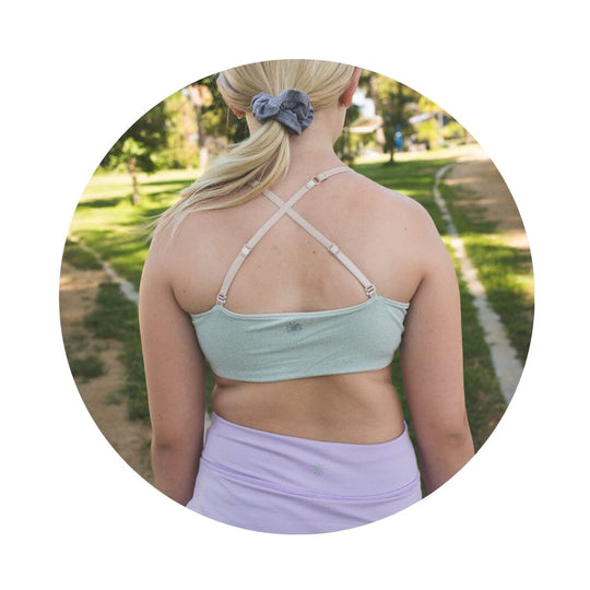 Sand-Sherbert#Close-up back view of a person with shoulder-length hair wearing a green Bleum Active Bra with crisscross straps.