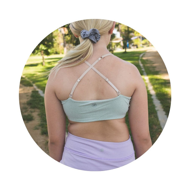 Sand-Sherbert#Close-up back view of a person with shoulder-length hair wearing a green Bleum Active Bra with crisscross straps.