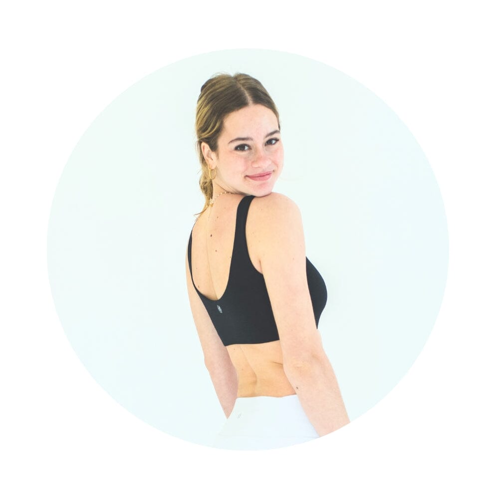 Black-Grey#A girl wearing a black Aster Organic Tank Bra from Bleuet. She is facing backward and smiling over her shoulder. Black-Grey#Organic Bras & Bralettes For Girls, Tweens and Teens