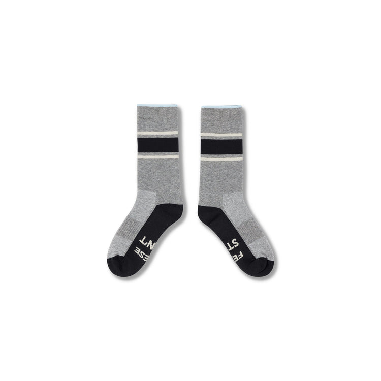 A pair of crew socks in heather gray with black and white stripes near the cuff, black toes and heels, and white text branding on the soles, shown against a plain white background.