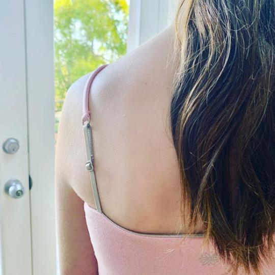 Close up of a tween girl wearing from behind wearing a ultra-soft seamless pink Bleuet Bleum girls first bras. View from back.