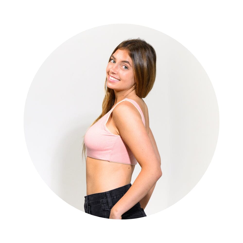 A woman with long brown hair is shown in profile wearing a light pink sports bra and black pants, set against a white circular background.