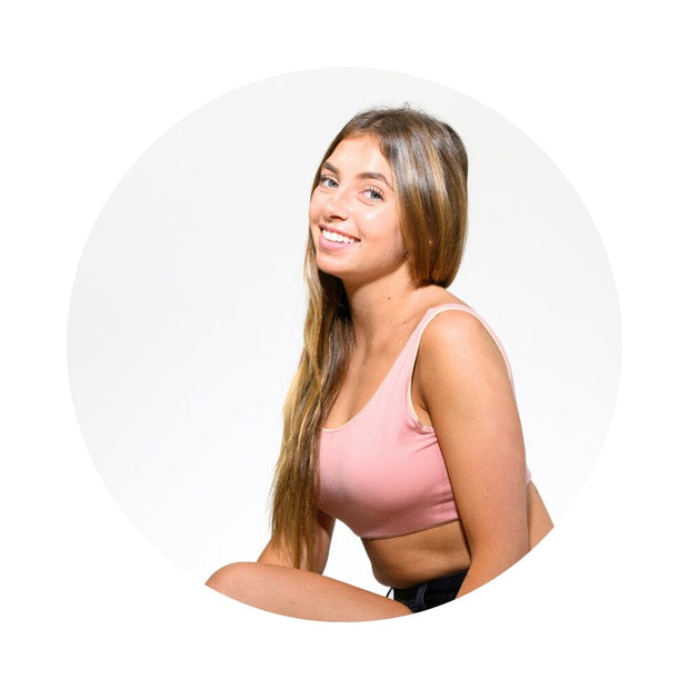 Sand-Rose#smiling young woman with long light brown hair wearing a light pink sports bra, shown inside a circular frame on a white background.