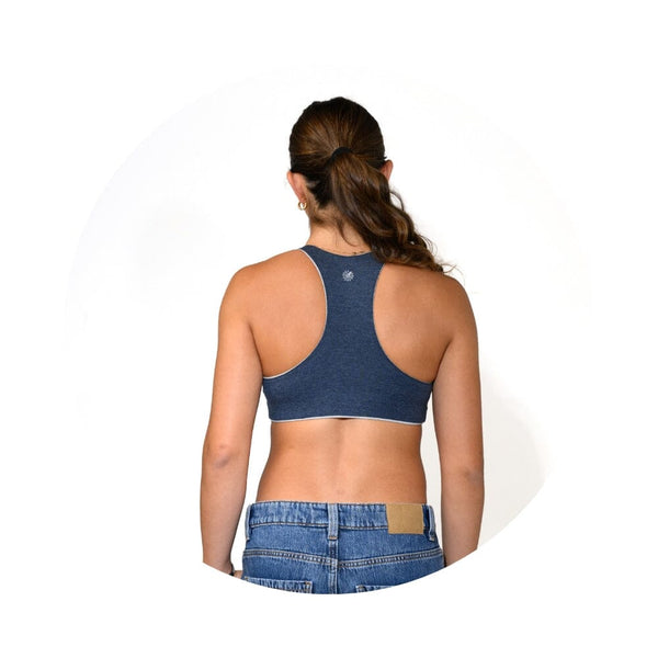 A woman shown from the back wearing a dark blue racerback sports bra and blue denim jeans against a plain white background.