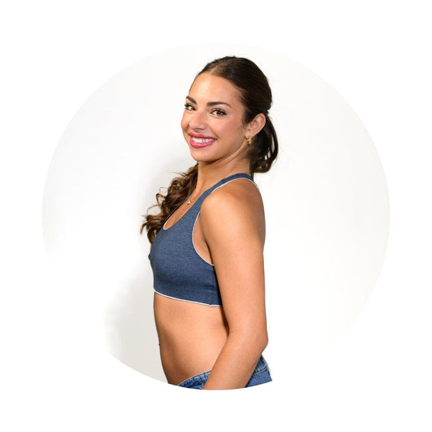 Grey-Lake#A woman with dark hair tied back is shown from the side wearing a heathered blue sports bra, set against a white circular background.