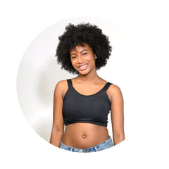 Black#A smiling young woman with a large black afro hairstyle wearing a black crop top and light blue denim jeans, set against a white circular background.