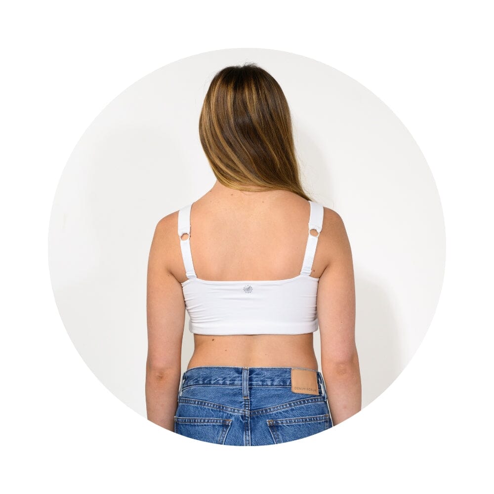 White#A woman viewed from behind wearing a white crop top with adjustable shoulder straps and blue jeans, centered inside a circular frame on a light gray background.