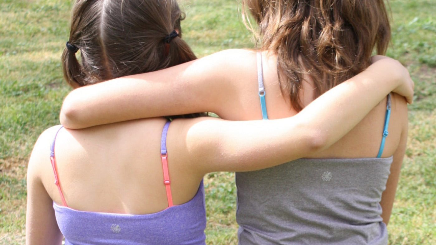 Two girls wearing purple and silver ultra-soft shelf-bra Bleuet Bleum camisoles in purples and silver in a park. View from back.