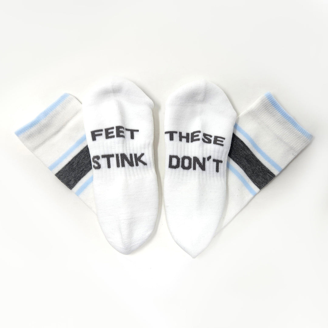 White#Two white ankle socks arranged in a fan shape on a white background. Two socks read 'FEET STINK' and two read 'THESE DON'T' in black text.