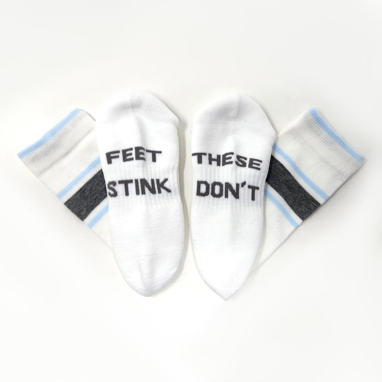 Two white ankle socks arranged in a fan shape on a white background. Two socks read 'FEET STINK' and two read 'THESE DON'T' in black text.