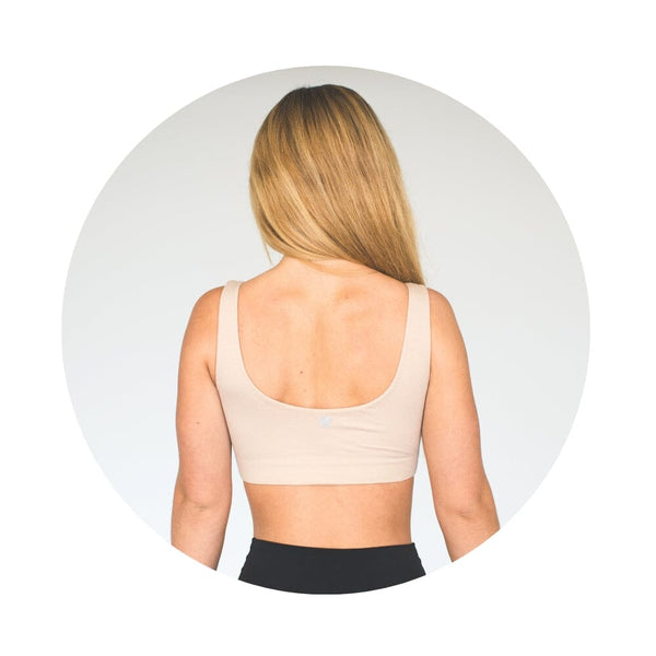 Back view of a woman with blonde hair wearing a beige organic tank bra.