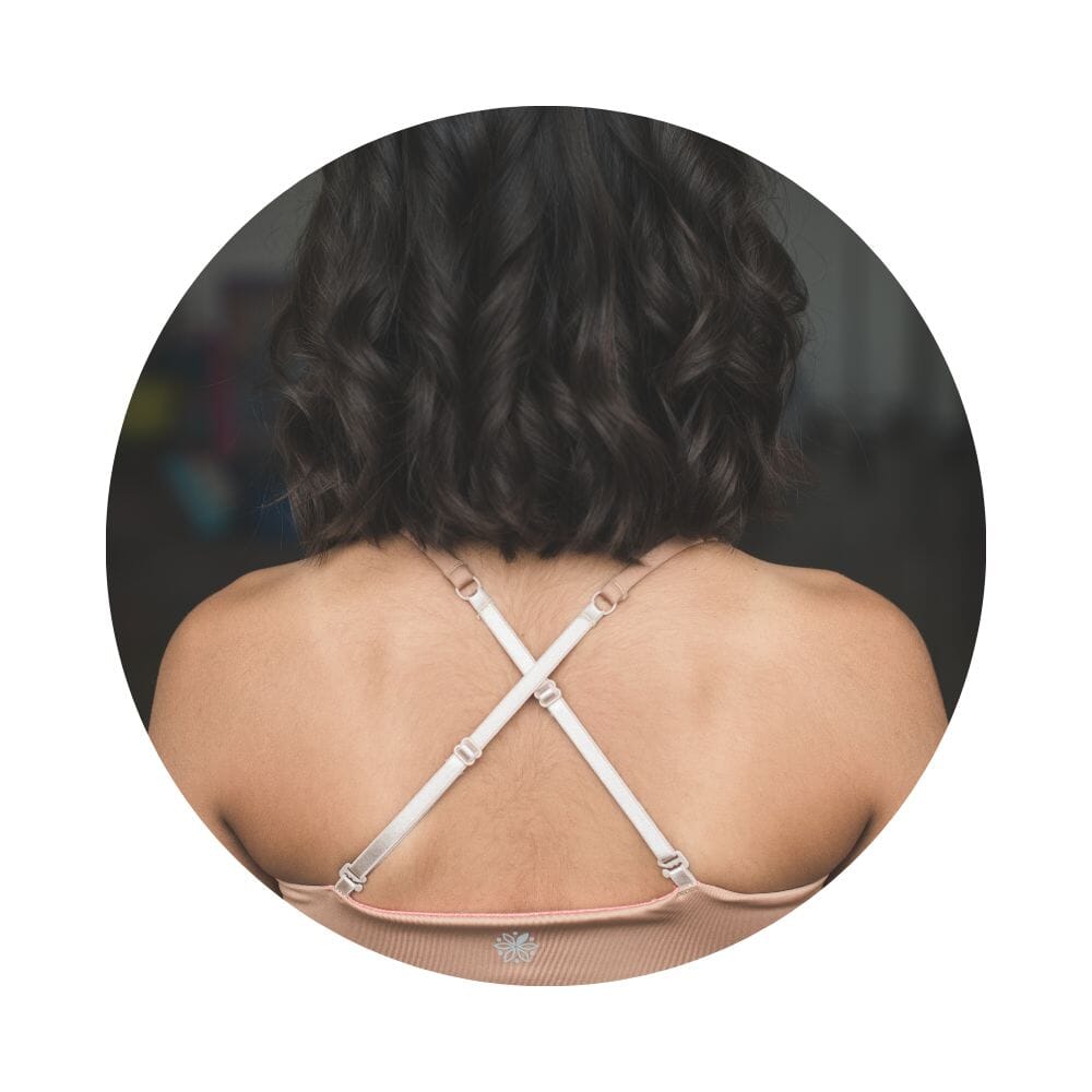 Caramel-Persimmon#Close-up back view of a person with shoulder-length hair wearing a beige Bleum Active Bra with crisscross straps.