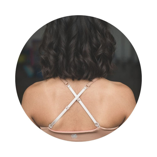 Caramel-Persimmon#Close-up back view of a person with shoulder-length hair wearing a beige Bleum Active Bra with crisscross straps.