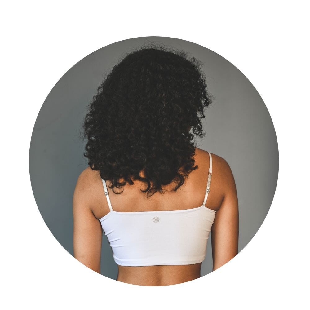 White-Dove#A girl with curly hair wearing a dove cami bra, viewed from the back.